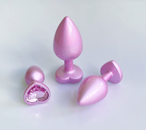 Różowe korki analne z sercem i kryształkiem w rozmiarach S, M i L. Eleganckie metalowe plugi analne z bezpieczną podstawą i dokładnymi wymiarami.