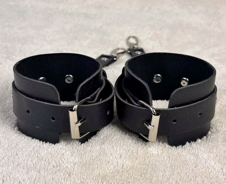 Regulowane kajdanki na ręce w kolorze czarnym. Miękki materiał, metalowe zapięcia, wygodne dopasowanie. Obwód 17,5–27,5 cm. Dyskretny i komfortowy model.